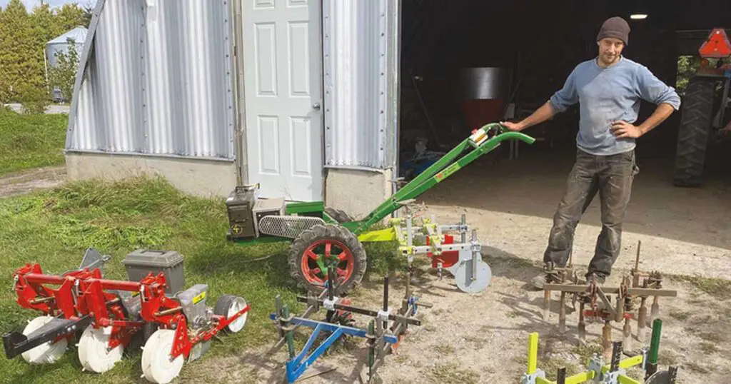 A young man stands among a selection of two-wheel tractors.