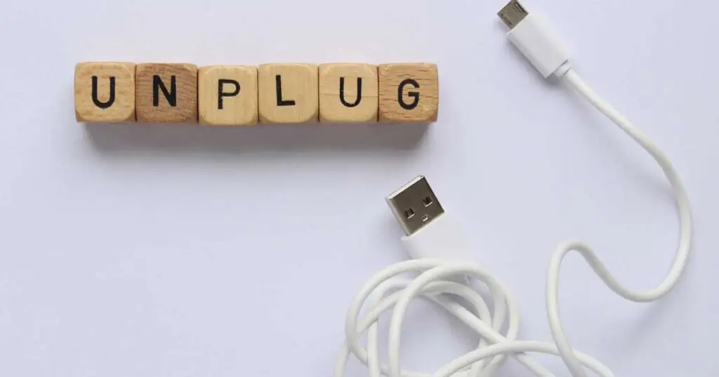 Unplug written in wooden blocks next to a phone charger