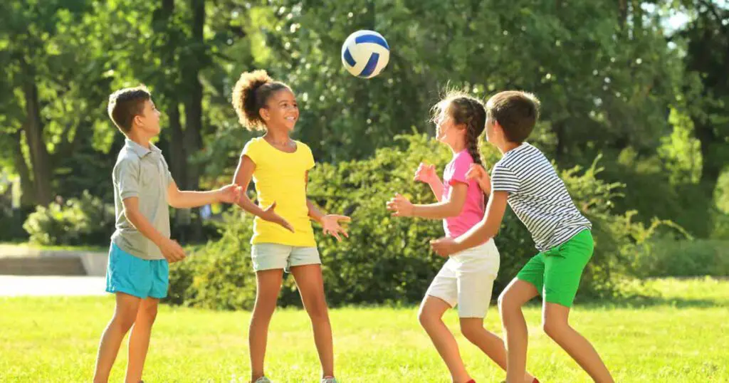 Four children throwing a volleyball in the air