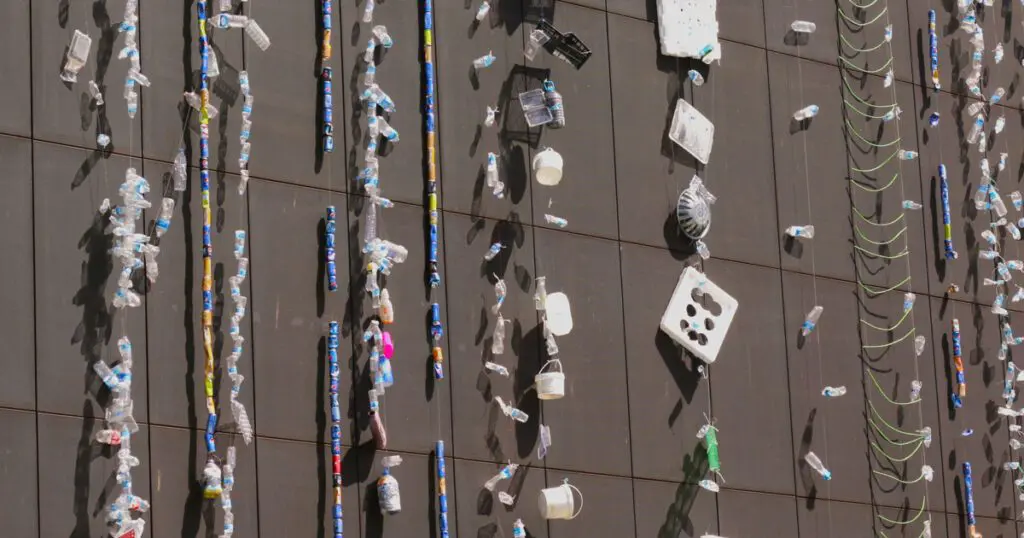 A large building with a plastic installation of trash hanging off the building