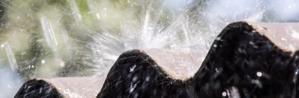 Rainwater splashes off a metal roof.