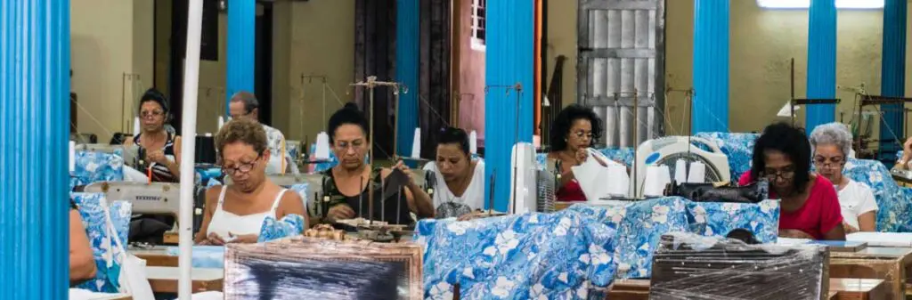 A rundown room full of women working on sewing machines.