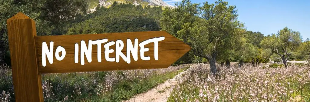 Rural field near the mountains with a wooden sign proclaiming No Internet.