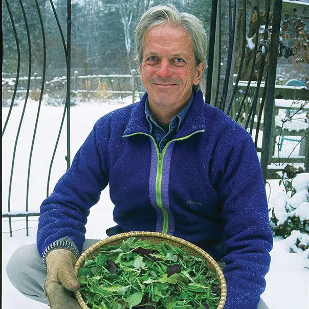 Farmer with a bowl of leafy greens outside in the middle of the winter.