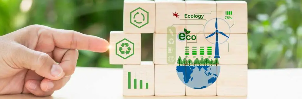 A finger pushes a block with the recycle symbol into a stack of eco-friendly designed blocks stacked in rows of four.