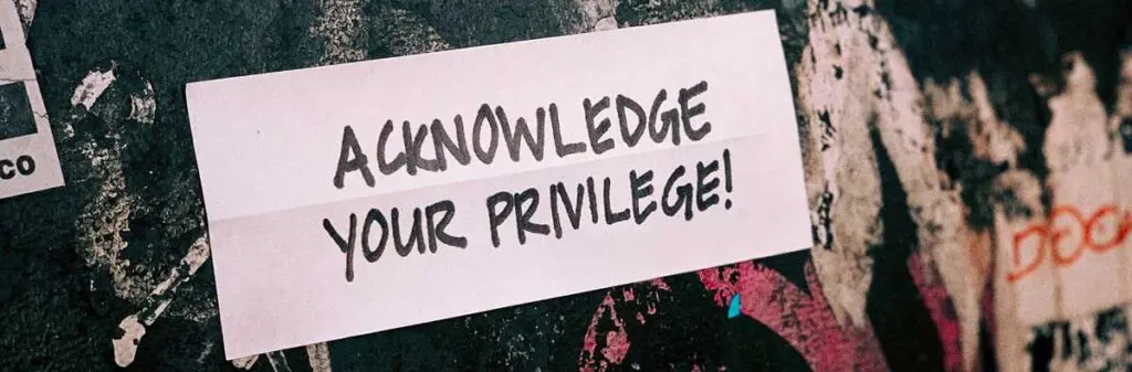 Acknowledge Your Privilege! sign on a multi-colored wall.