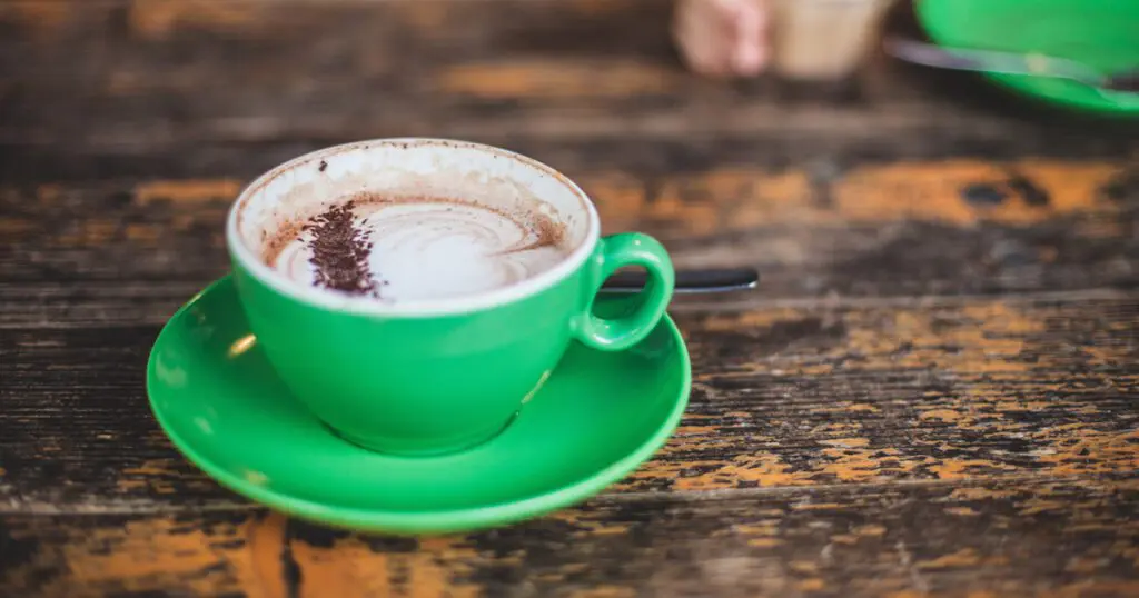 A delicious-looking cup of hot chocolate with foam and chocolate sprinkles.