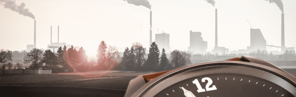 Clock with an industrial skyline as the background, emitting smoke under a dimly lit sky, serves as a poignant reminder of our need for Climate Action.