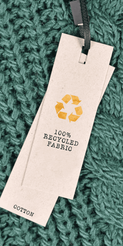 Tag with "100% Recycled Fabric" text on a textured green background, perfect for conscious gifting.