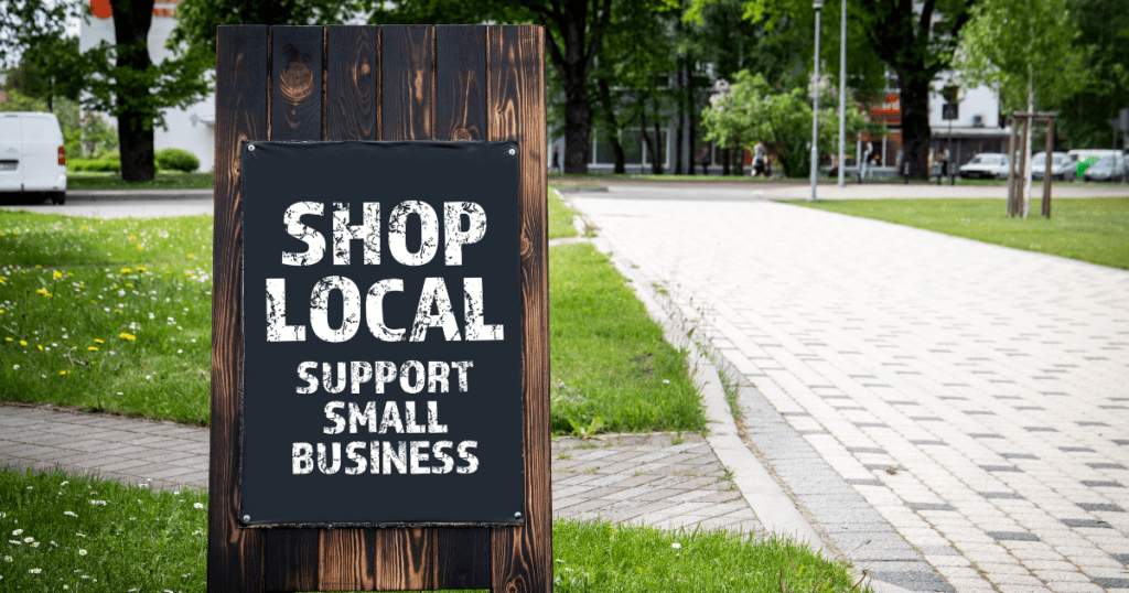 Chalkboard sign on a park path reads "Shop Local, Support Small Business," offering insight into how to support local entrepreneurs.