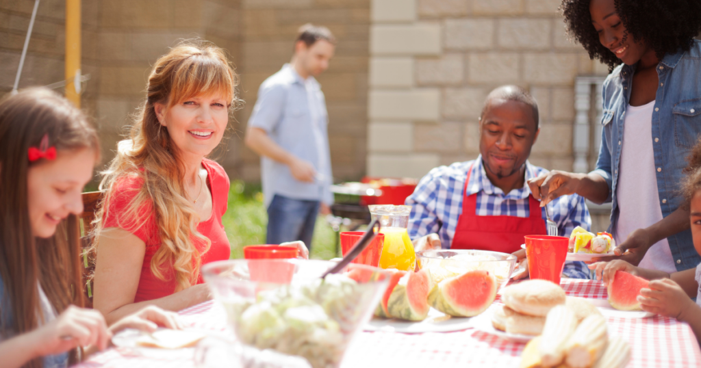 People enjoying a picnic table with watermelon and drinks, embracing modern communal living.