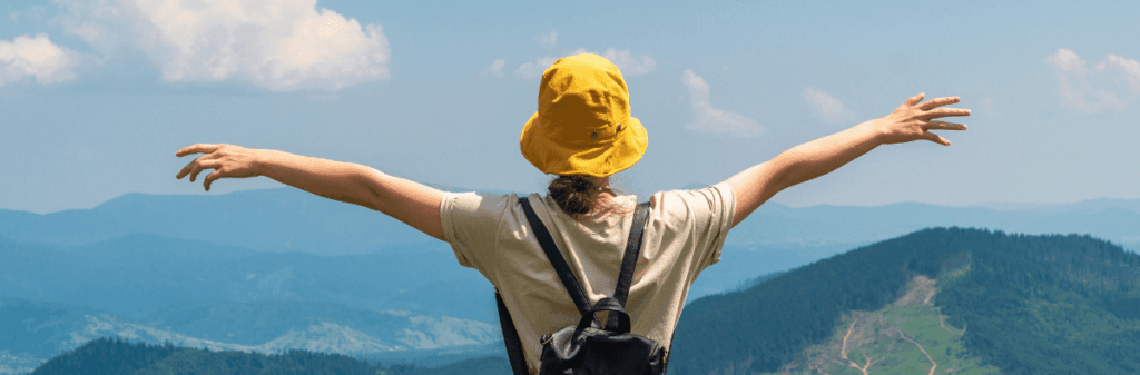 Enjoy nature without hurting it. Woman takes in the view of the mountains with arms outstretched.