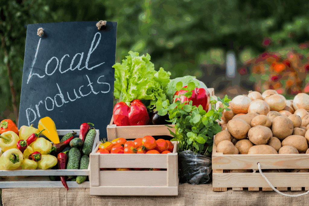 Fresh local vegetables and small fruit growing showcased in crates beside a "Local products" sign.