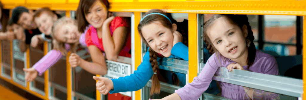 Back to school joy, smiling children lean out of the windows of a school bus.
