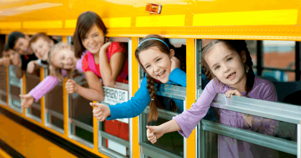 Back to school, children smiling and leaning out of windows on a yellow school bus, radiating Summer Joy.