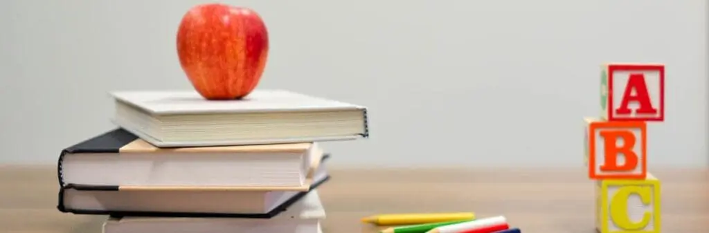 Stacked books with an apple, ABC blocks, and Jim Rietmulder’s When Kids Rule the School.
