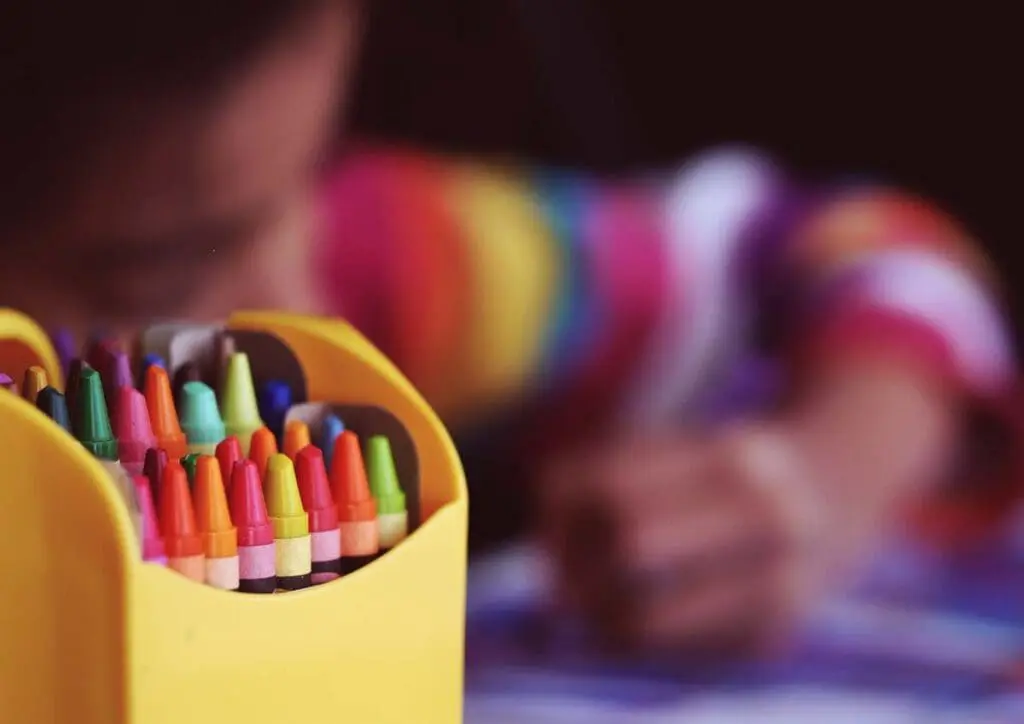 A box of colorful crayons with a child coloring, inspired by When Kids Rule the School.