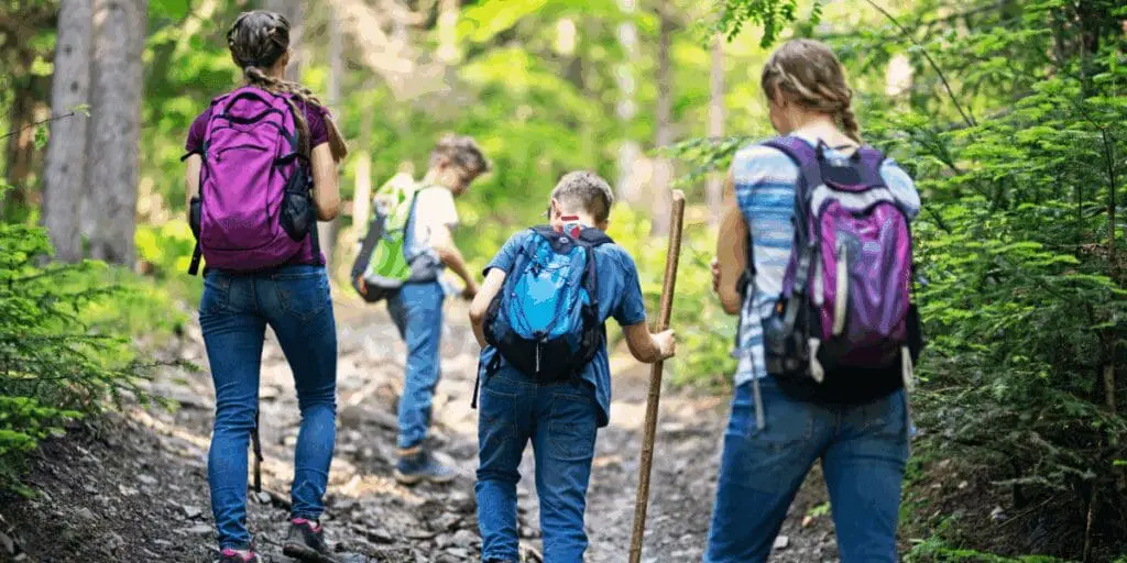 Back to school, four kids with backpacks hiking, savoring the joy of summer adventures.