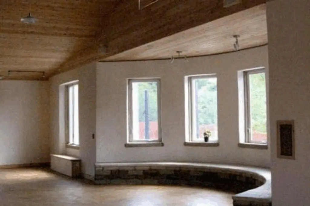 Curved stone bench under four windows; ideal for eco-friendly hempcrete construction projects.