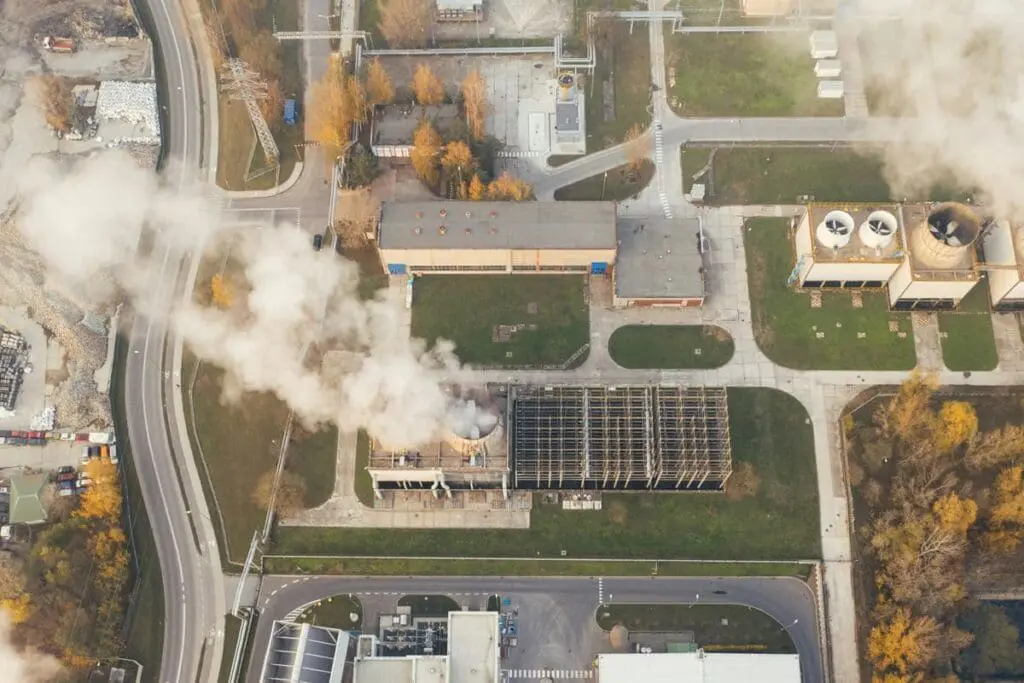Aerial view of a factory emitting 2.5 tonnes of smoke, surrounded by autumn trees and roads.