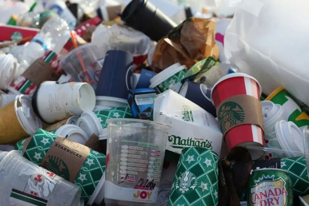 A pile of discarded cups and containers hints at the 2.5 tonnes carbon math magic number.
