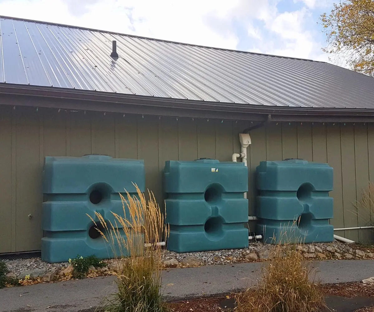 Three large blue rainwater tanks support water security beside a building with green walls.