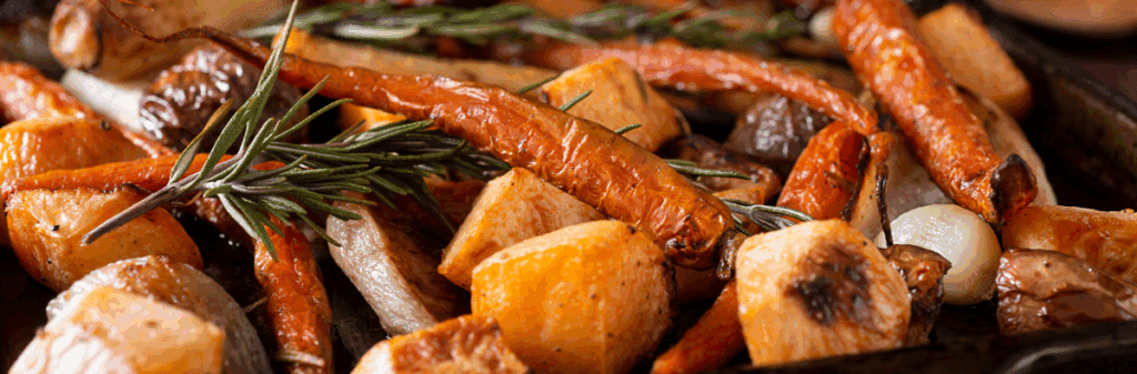 Roasted root vegetables—carrots, potatoes, and herbs—on a baking tray.