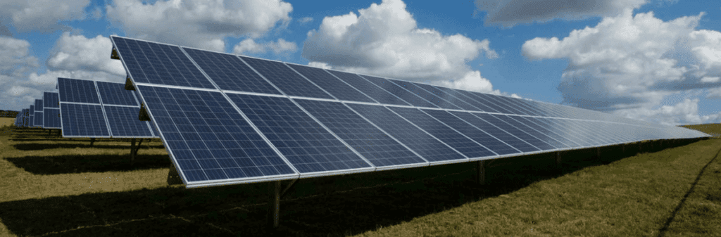 Rows of solar panels in a field harness clean power under a partly cloudy sky.