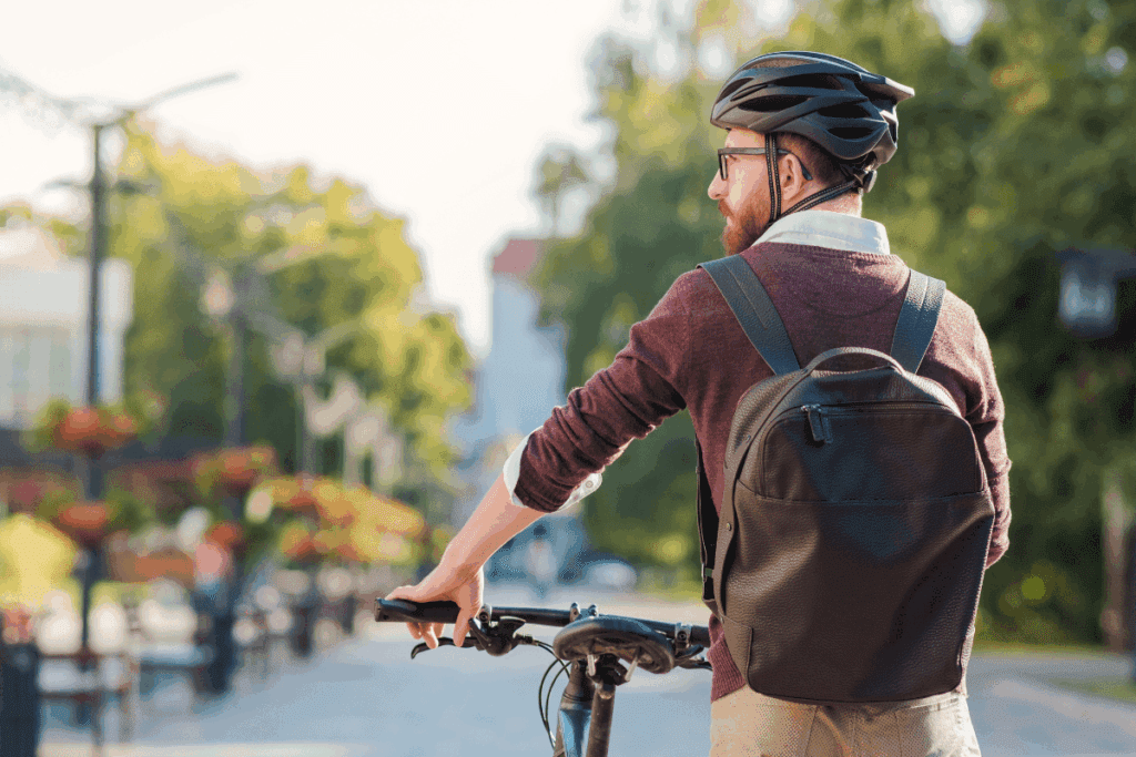 Man with backpack and helmet stands by bicycle, showcasing energy and sustainability.