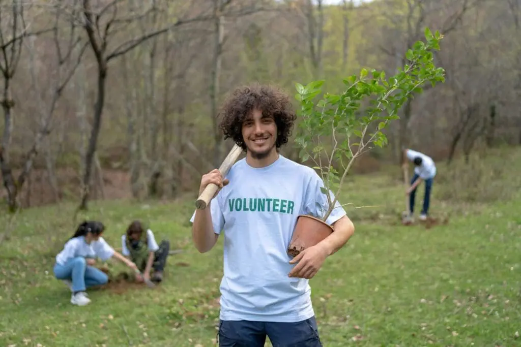 Smiling volunteer with kids planting trees, taking action on climate change for 2025.