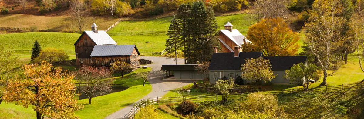 A scenic rural farm with barns, a farmhouse, trees, and a chicken coop in early autumn.