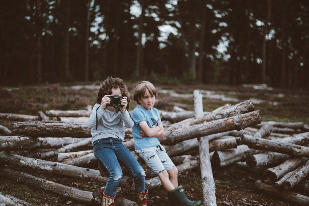 Two boys sitting on the start of a wooden fort