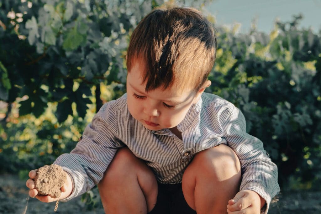A young boy crouched down playing with sand