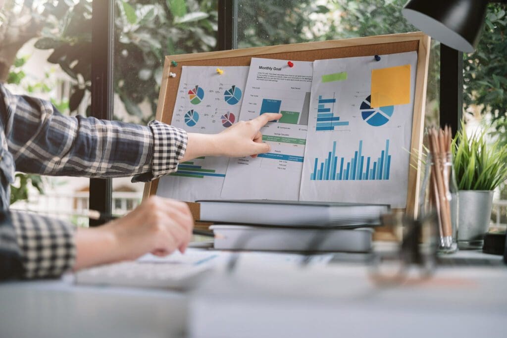 Charts and graphs on a board with a person pointing to them