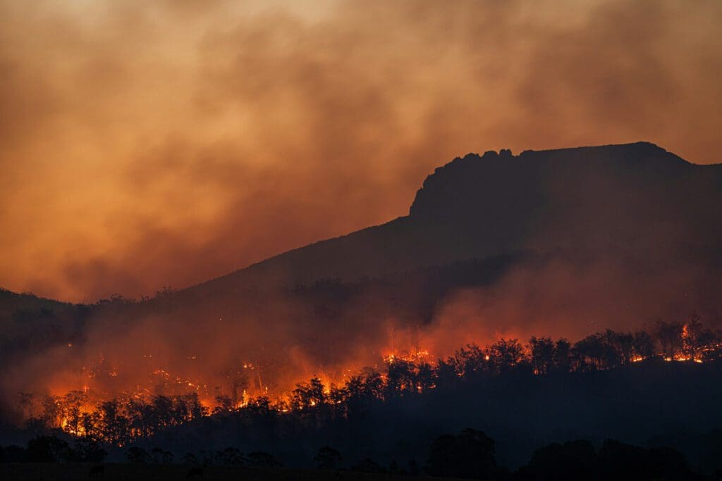A mountain on fire with yellow / orange smokey skies