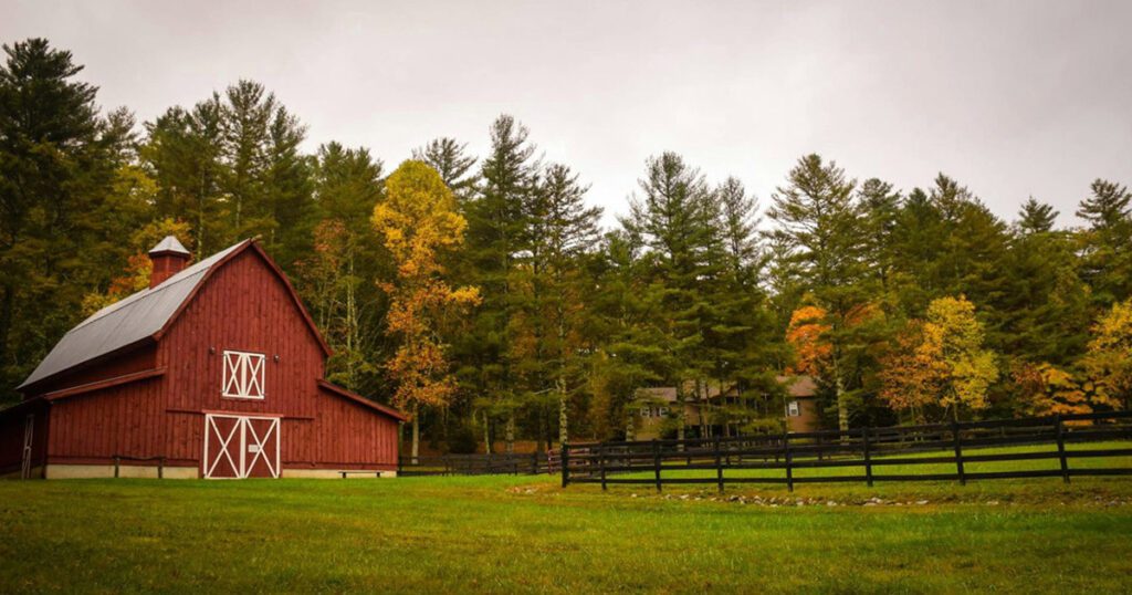 Red barn surrounded by lawn and forest