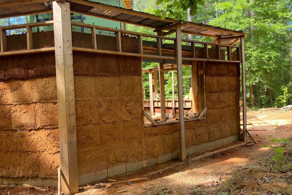 A clay and sand frame and supporting wood pillars and window holes.