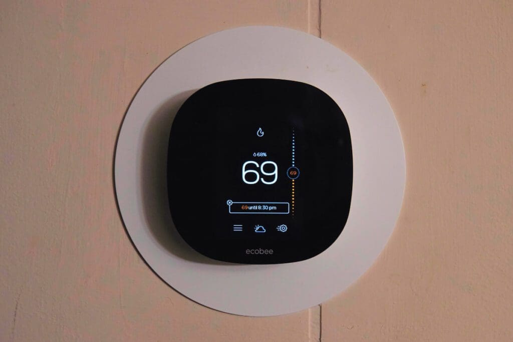 A digital thermostat on a wall shows 69 degrees.