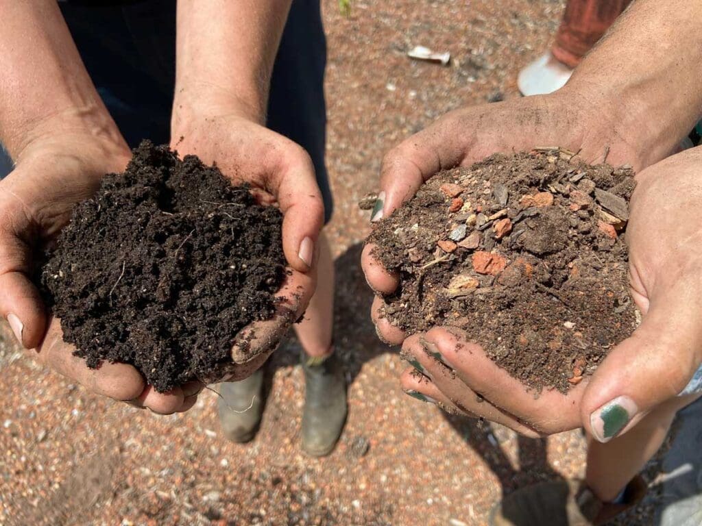 Two people holding handfuls of soil for comparison.
