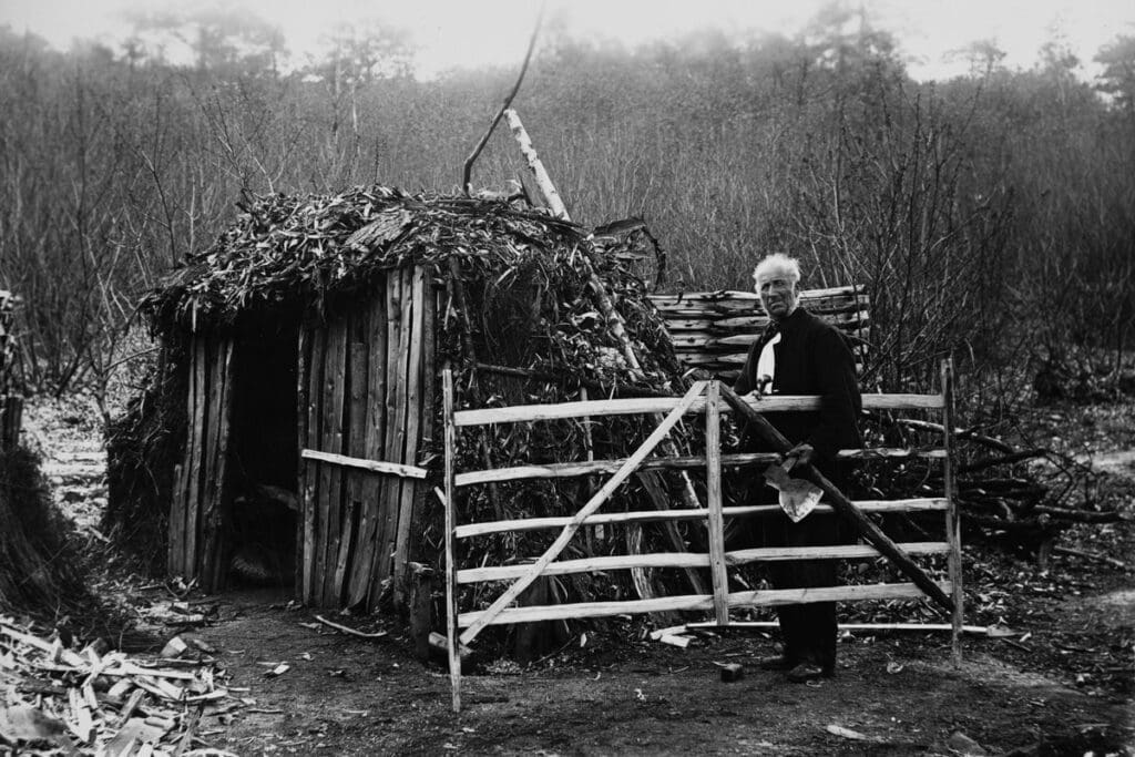 Gate hurdle maker and hut in Surrey, UK, possibly near Elstead. Note the wood shavings covering the hut, the stack of completed hurdles behind him, and the large hewing hatchet in his left hand. Photo courtesy of the Museum of English Rural Life, University of Reading, used by permission.