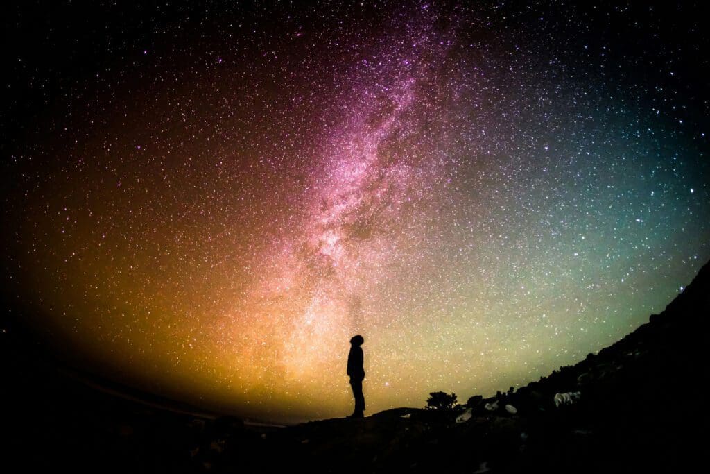 Silhouette of a man looking up at a glowing starry sky