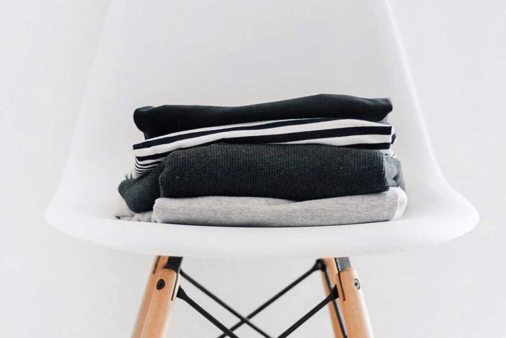 A small stack of clothes (shirts) sitting on a white plastic chair.