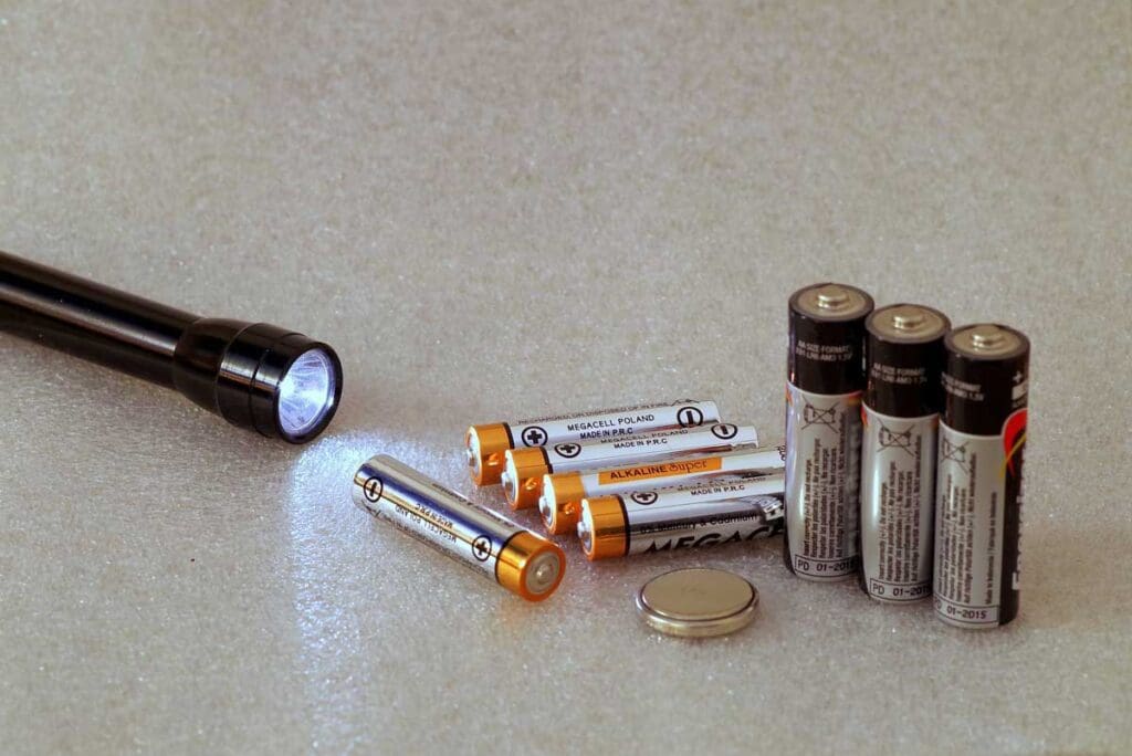 A lit flashlight and an assortment of batteries.