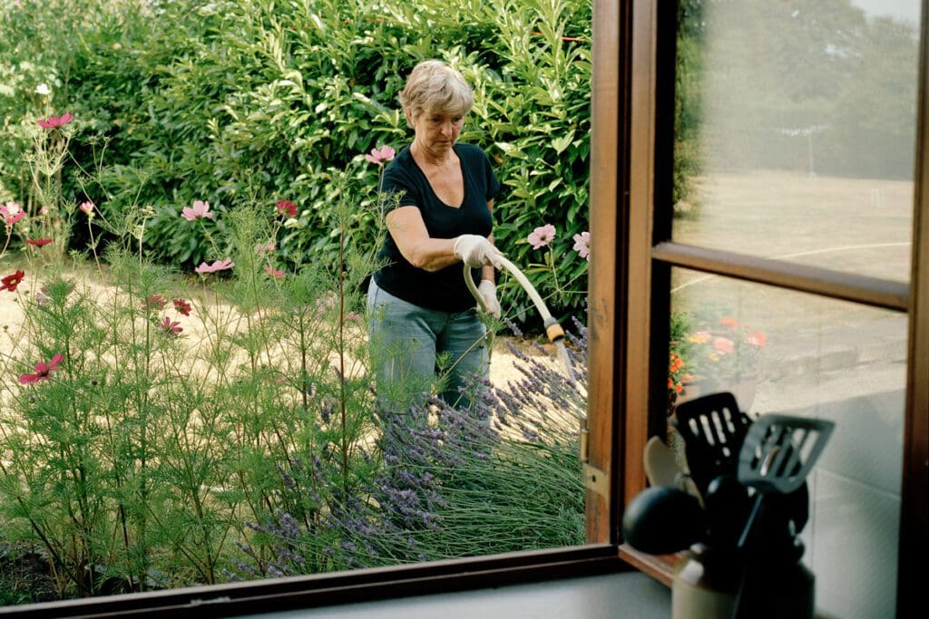 A woman watering her garden with a hose.