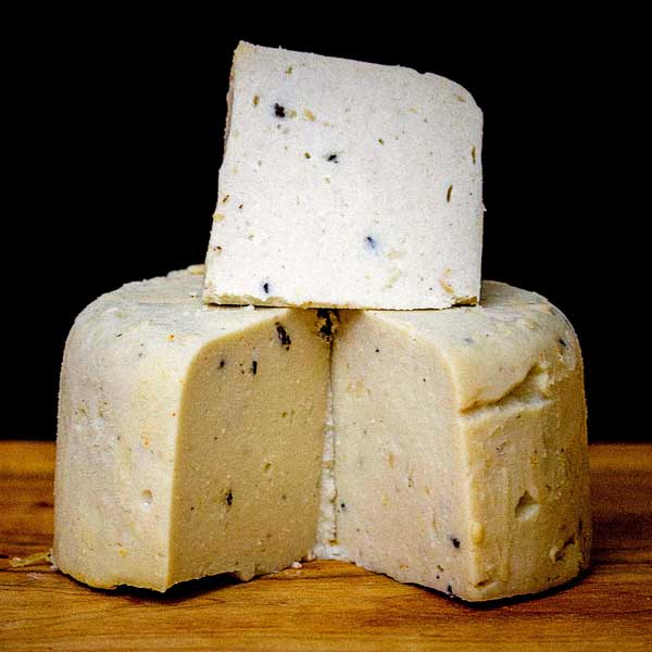 A large mound of plant-based cheese with quart-sized piece cut and sitting on top.