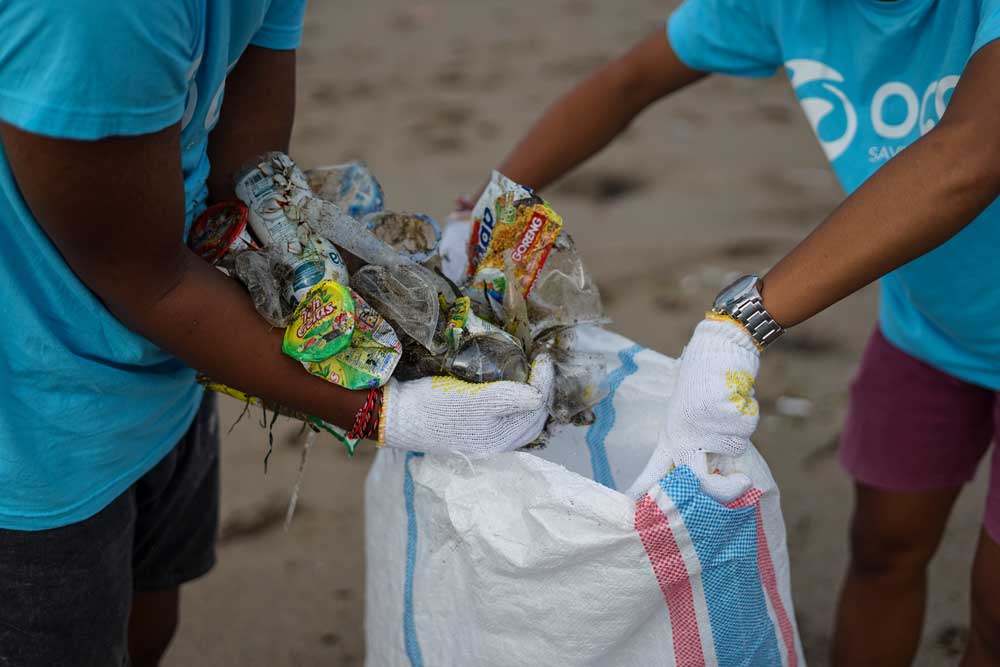 Two volunteers put trash into bags.