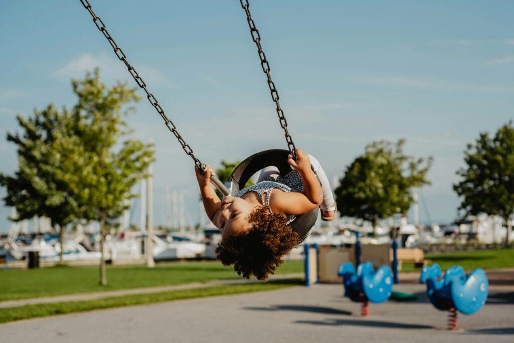 A young girl swings hight on a park swing set, looking upside down.