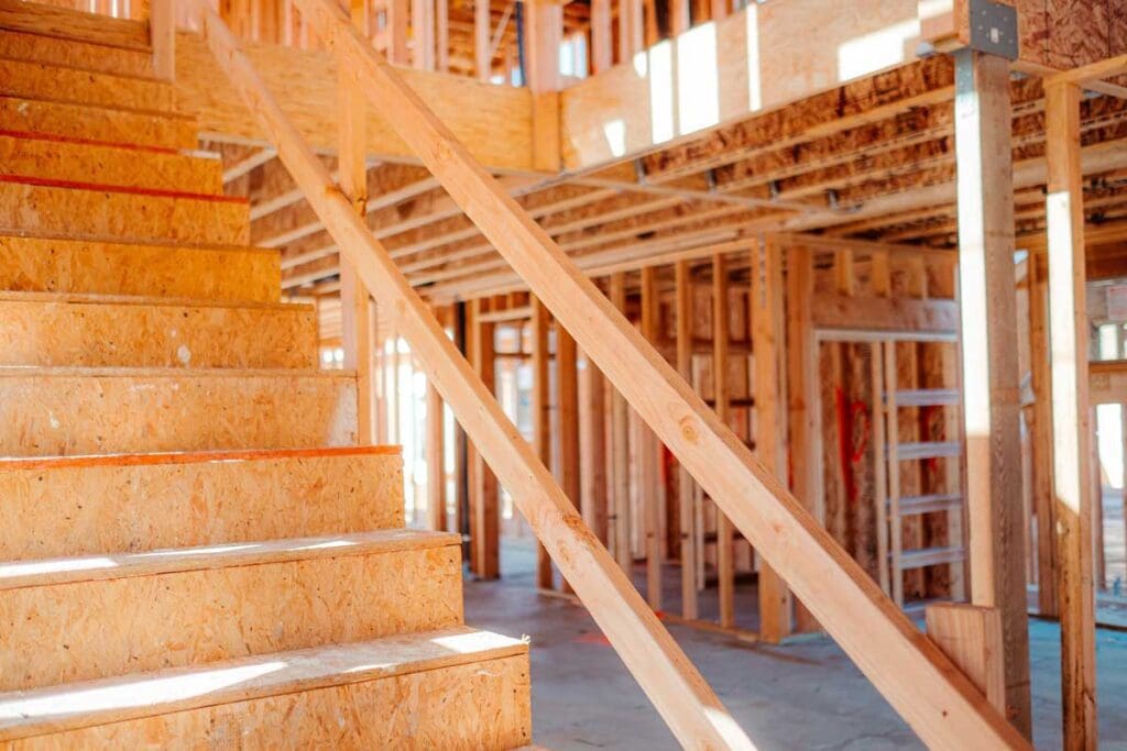 Interior framing of a new home's first floor and stairway under construction.