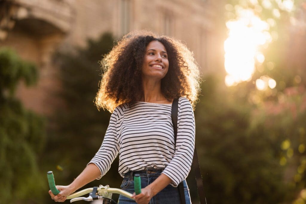 A smiling woman walking with a bike