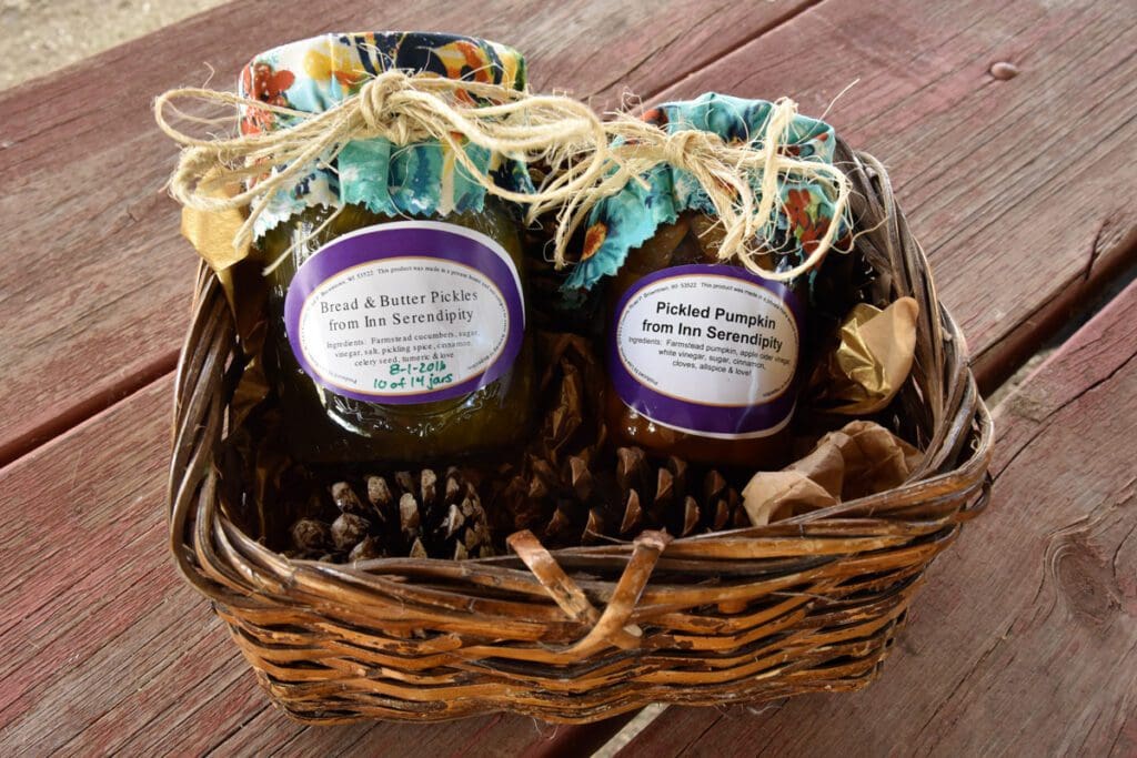 Jars of preserves (Bread & Butter Pickles and Pickled Pumpkin) in a wicker basket.